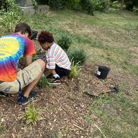 One of the kids and previous intern Mitch planting a Spiderwort plant