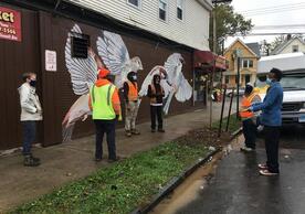 Kwadwo Adae and GreenSkills planting crew in front of mural and tree